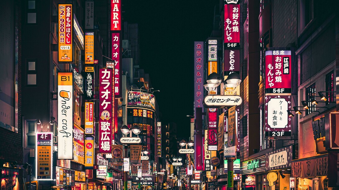 Night view of a busy street in Shinjuku, Tokyo, illuminated by vibrant neon signs and crowds of pedestrians, Japan