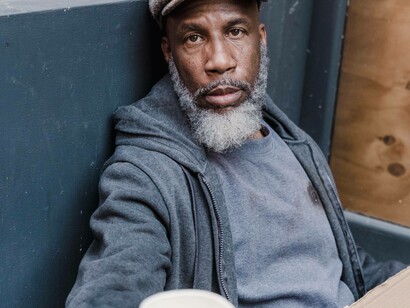 Homeless man uses a cup to ask for donations