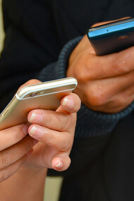 Two individuals utilizing mobile phones and technology