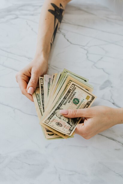 A person holding some money on a white table