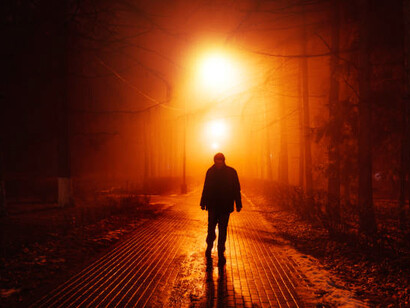 In the fog-shrouded park at night, a solitary man walks, capturing the essence of isolation and silent resistance