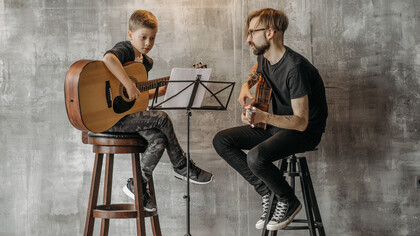 Professor de violão clássico dando aula a um jovem aluno