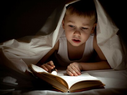 Uma criança lê na cama antes de dormir