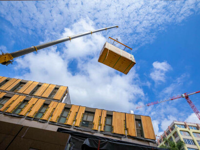 Crane assembling a prefabricated modular wooden commercial building, highlighting streamlined and efficient construction methods