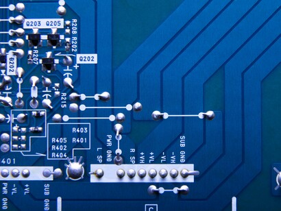Delicate electronic circuits branching across a blue circuit board, symbolizing the invisible infrastructure powering modern society