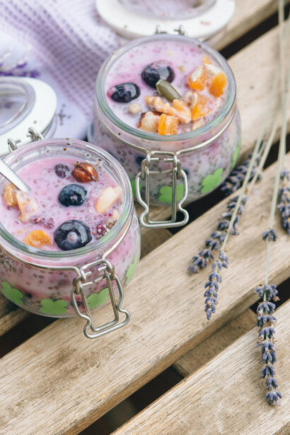 Two glass jars of chia seed pudding with fresh fruit toppings served outdoors with lavender sprigs