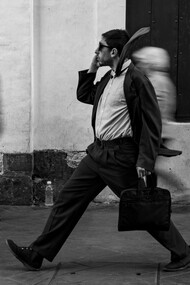 A focused man moving through a blur of rushing pedestrians, representing the modern pressure to stay constantly occupied
