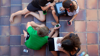 Niños jugando con ordenadores, móviles y tabletas