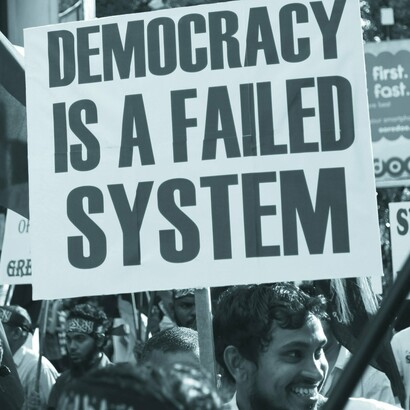 Manifestante en Maldivas sosteniendo un cartel que dice: "La democracia es un sistema fallido"