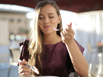 Woman in a purple top slicing pizza at a long Italian-style lunch