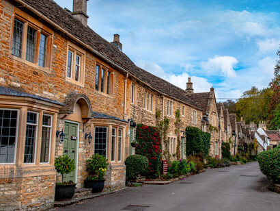 A street lined with stone buildings and trees in the picturesque village of Castle Combe, Chippenham, UK