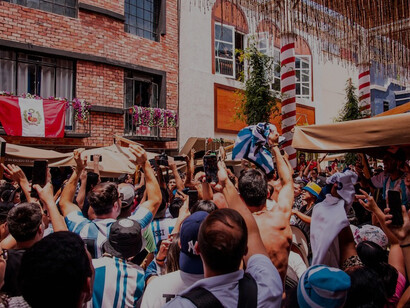 In the vibrant neighborhood of Miraflores, Peru, a lively crowd gathers in front of a building, anticipating the upcoming FIFA World Cup in 2022