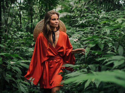 In the heart of Bali, Indonesia, a woman donned in a vibrant red dress explores the forest solo, becoming one with the natural allure that surrounds her