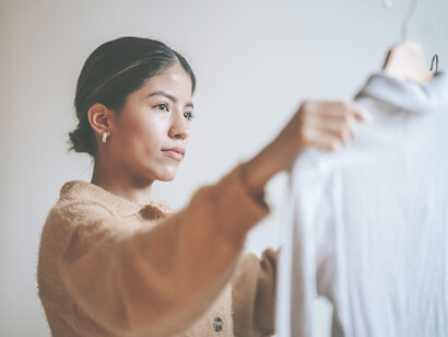 Mujer seleccionando ropa. Realizar ejercicios en donde utilizamos con consciencia el exterior para generar cambios en el interior —por ejemplo, experimentar con la vestimenta para mostrar apertura—, es usarla a nuestro favor