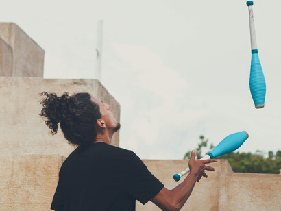 A backside view of a curly man juggling clubs