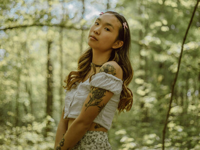 Tattooed woman in a white blouse in the forest
