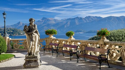 A statue sits on a bench overlooking Lake Como at Villa del Balbianello in Italy