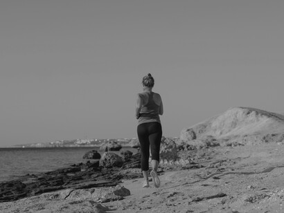 The woman takes a jog near the ocean on the sand