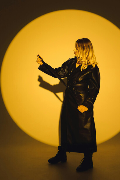 Modella in trench di pelle nero su set fotografico di sfondo giallo