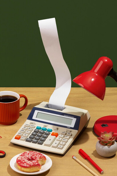 Calculator, donut, and coffee on a desk representing efficient food cost calculation and ingredient pricing strategies for café profitability