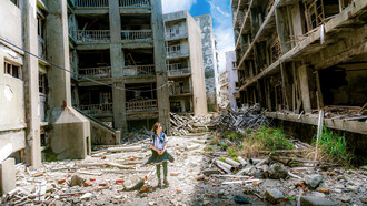 A girl walks amidst a wrecked and war torn city