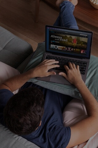 A man scrolling through a streaming service on his tablet, selecting a movie to watch