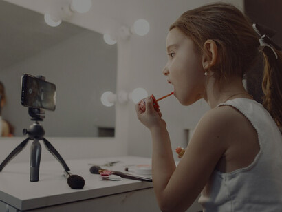 A young girl applying makeup and recording a video at home, children and beauty products, the early use of cosmetics by young girls, and the impact on childhood self-image