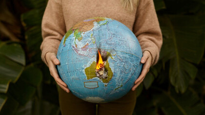 In the palm of a woman's hand, a burning globe symbolizes the urgency of the climate crisis