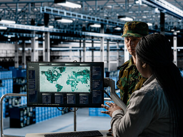 Defense personnel monitoring target coordinates in a modern military operations center