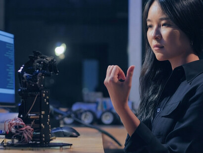 A female engineer tests a robotic hand in a research laboratory