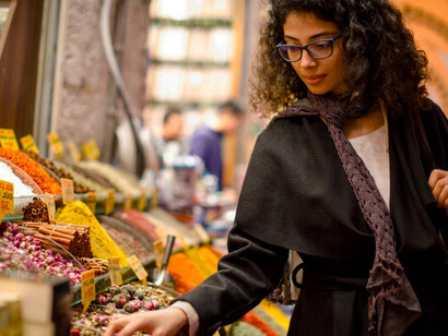 A woman browsing a colorful spice shop in Istanbul’s Grand Bazaar, Turkey