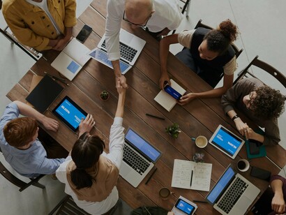 People discussing at a table with laptops
