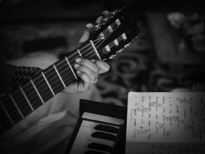 Persona tocando una guitarra siguiendo notas musicales