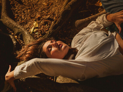 Woman lying peacefully on the forest floor under soft sunlight