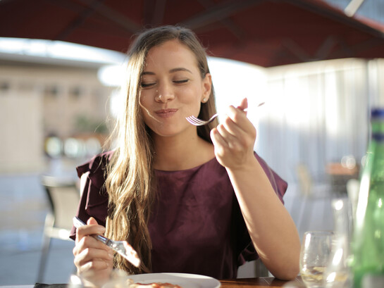 A woman in purple enjoys her meal, taking time to savor each bite