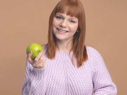 Managing food intolerance as a woman holds an apple, illustrating the careful choices and challenges involved in navigating dietary restrictions