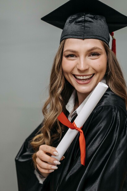 Woman with a graduation gown holding a diploma
