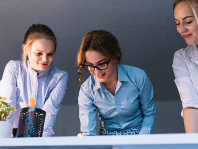 A team of young, innovative businesswomen brainstorming and collaborating on a creative project in a contemporary office setting