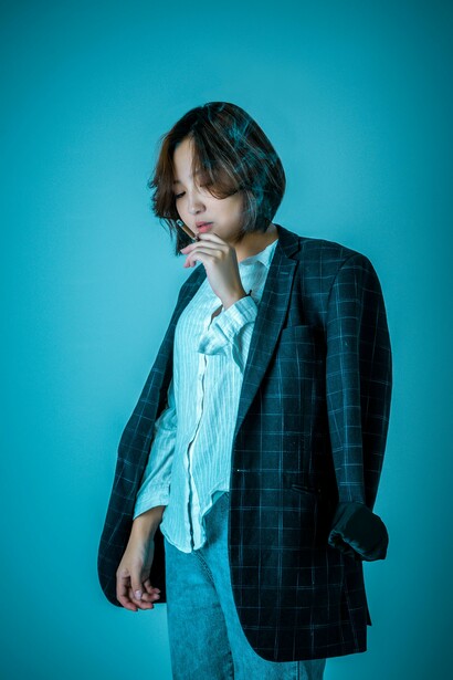 A person wearing a shirt and a blazer smoking a cigarette