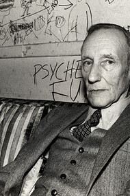 The writer, William Burroughs, at a dive bar dressed in a three-piece suit