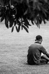 Homem sentado ao chão, desolado. A tristeza que pode ser causada por distorções da sociedade