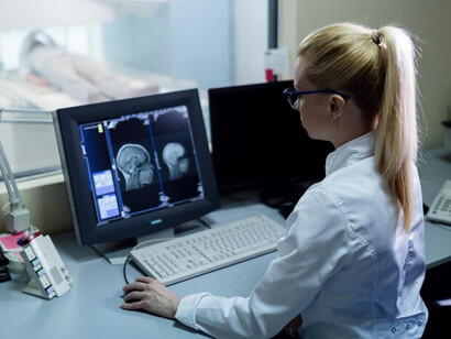 In the control room, a radiologist analyzes the results of a patient's brain MRI scan on a computer screen