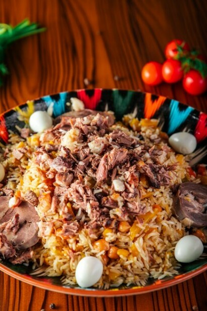 On a wooden table rests a colorful plate of plov, showcasing the heart of traditional Uzbek cuisine