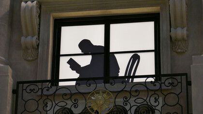 Ombra di un uomo alla finestra intento nella lettura di un libro