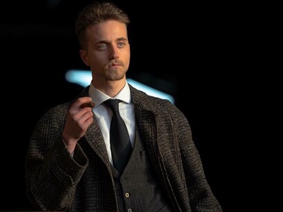 A man holding a cigar wearing tweed