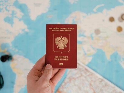 A passport held before a world map, representing the movement of talent across international borders