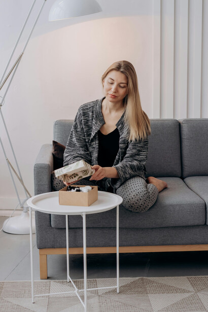 Woman in a black-and-white long-sleeve dress sitting on a grey couch at home