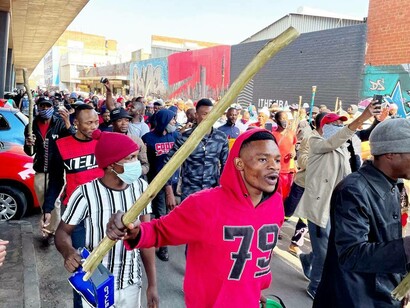 South African protesters marching, chanting, and wielding weapons in the middle of the Covid-19 pandemic to voice their frustrations