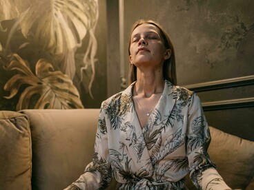 A woman sits quietly on a couch, practicing mindfulness in a calm, softly lit interior