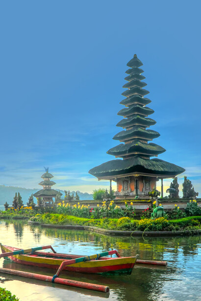 A canoe on a calm lake with a pagoda in the background in Bali, Indonesia